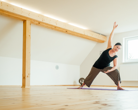 Frau macht eine Yoga-Übung in einem lichtdurchfluteten Raum