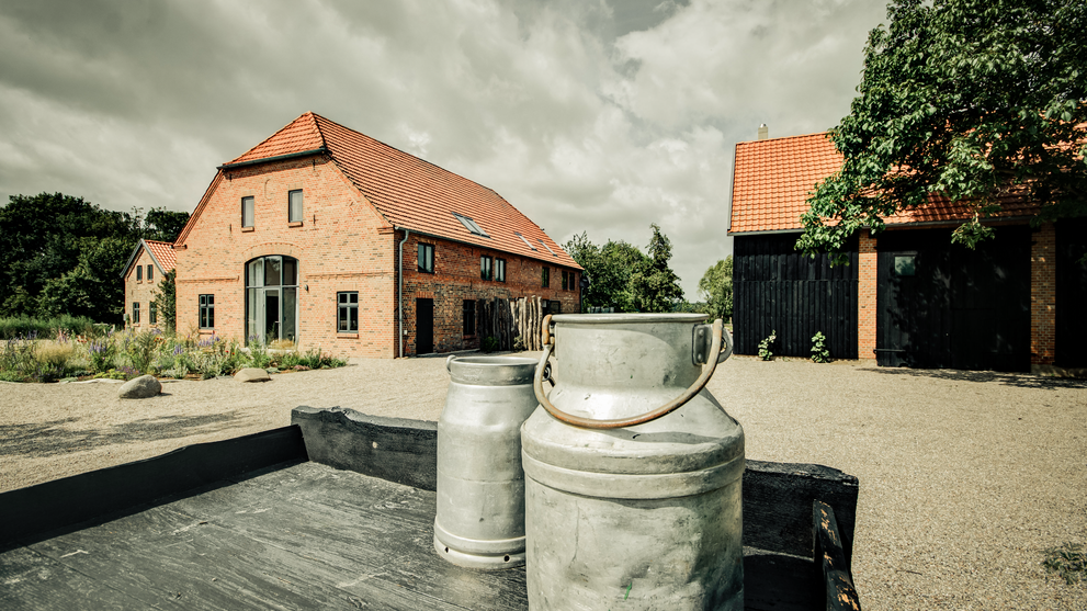Hofbereich mit Gebäuden und Milchkannen im Vordergrund