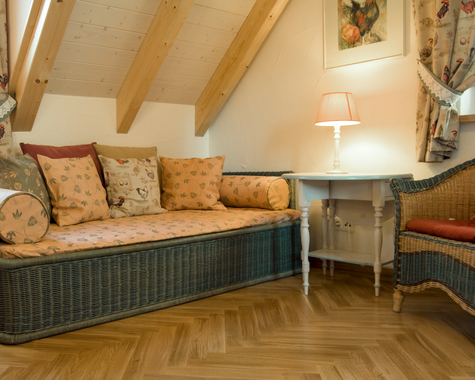 Sitzecke mit Korbsesseln, gemustertem Sofa und Dachschräge