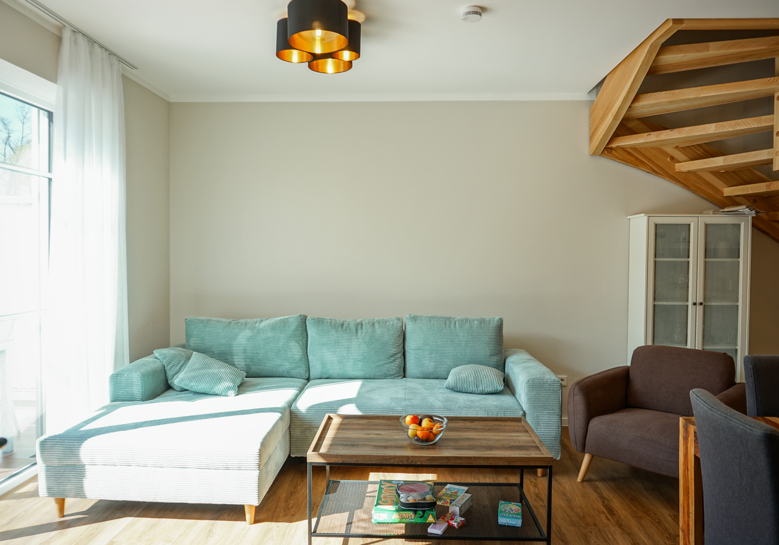 Wohnbereich mit türkisem Sofa, Couchtisch und Dachschräge