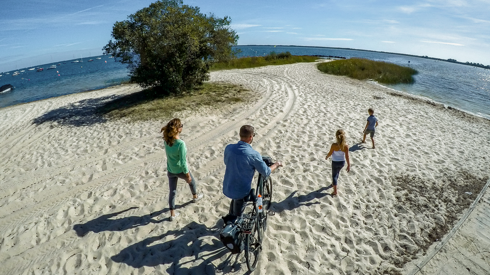 Familie läuft über den Strand am Meer, umgeben von Wasser auf beiden Seiten