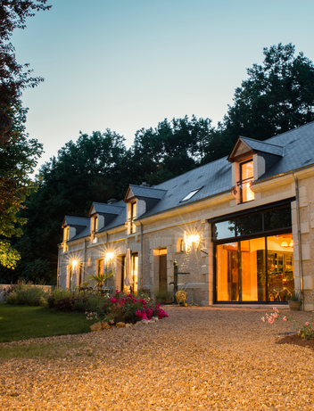 Modernes Ferienhaus mit beleuchteten Fenstern und Garten in der Abenddämmerung