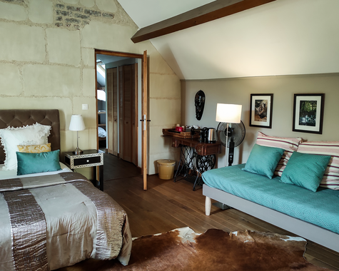 Wohn-Schlafbereich mit türkisem Sofa und Holzboden