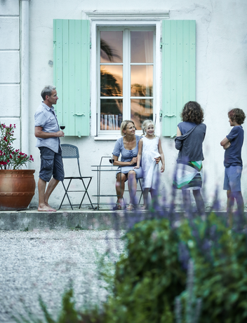 Familie steht auf einer Terrasse eines modernen Ferienhauses mit Blick in den Garten