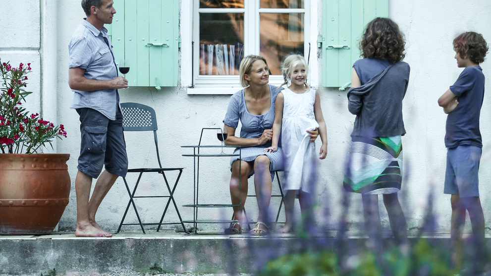 Familie steht auf einer Terrasse eines modernen Ferienhauses mit Blick in den Garten