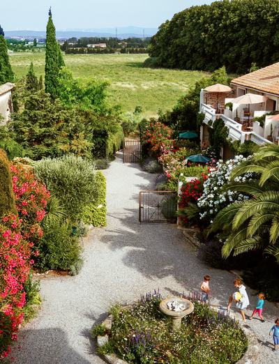 Mediterraner Innenhof mit üppigen Pflanzen, Blumen und Blick in die Natur