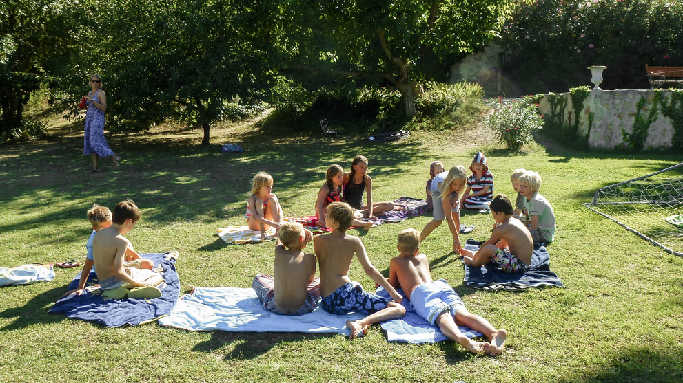 Kinder sitzen auf Decken auf einer Wiese 