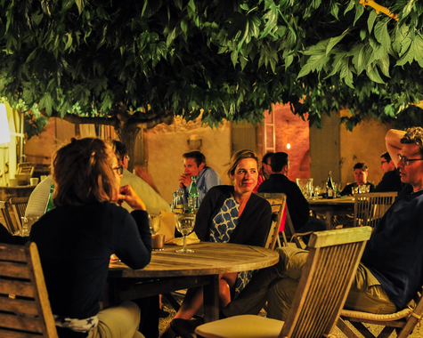 Gruppe von Menschen sitzt abends gemeinsam an einem Tisch im Garten