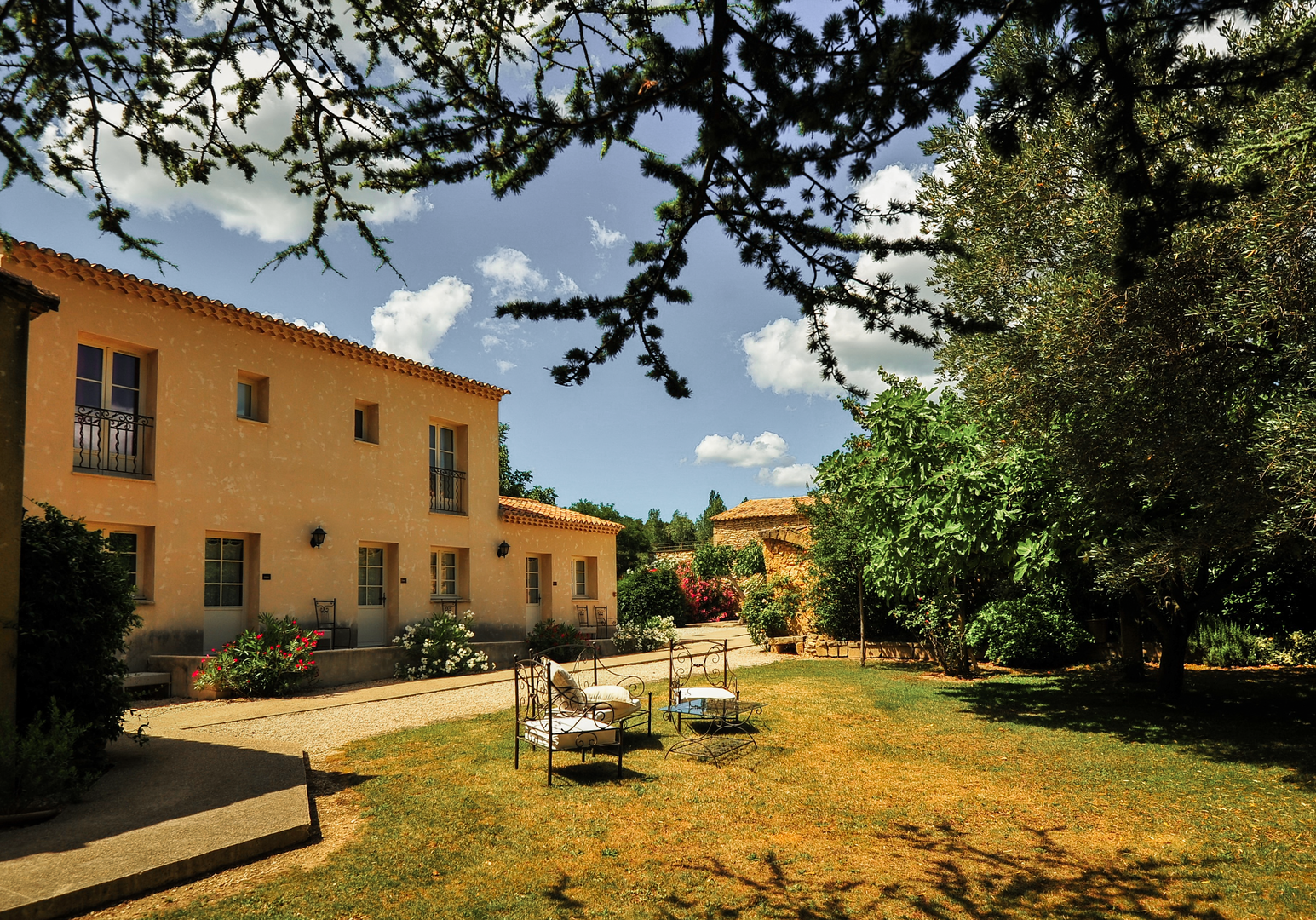 Landhaus mit Garten und Sitzmöglichkeiten im Schatten von Bäumen