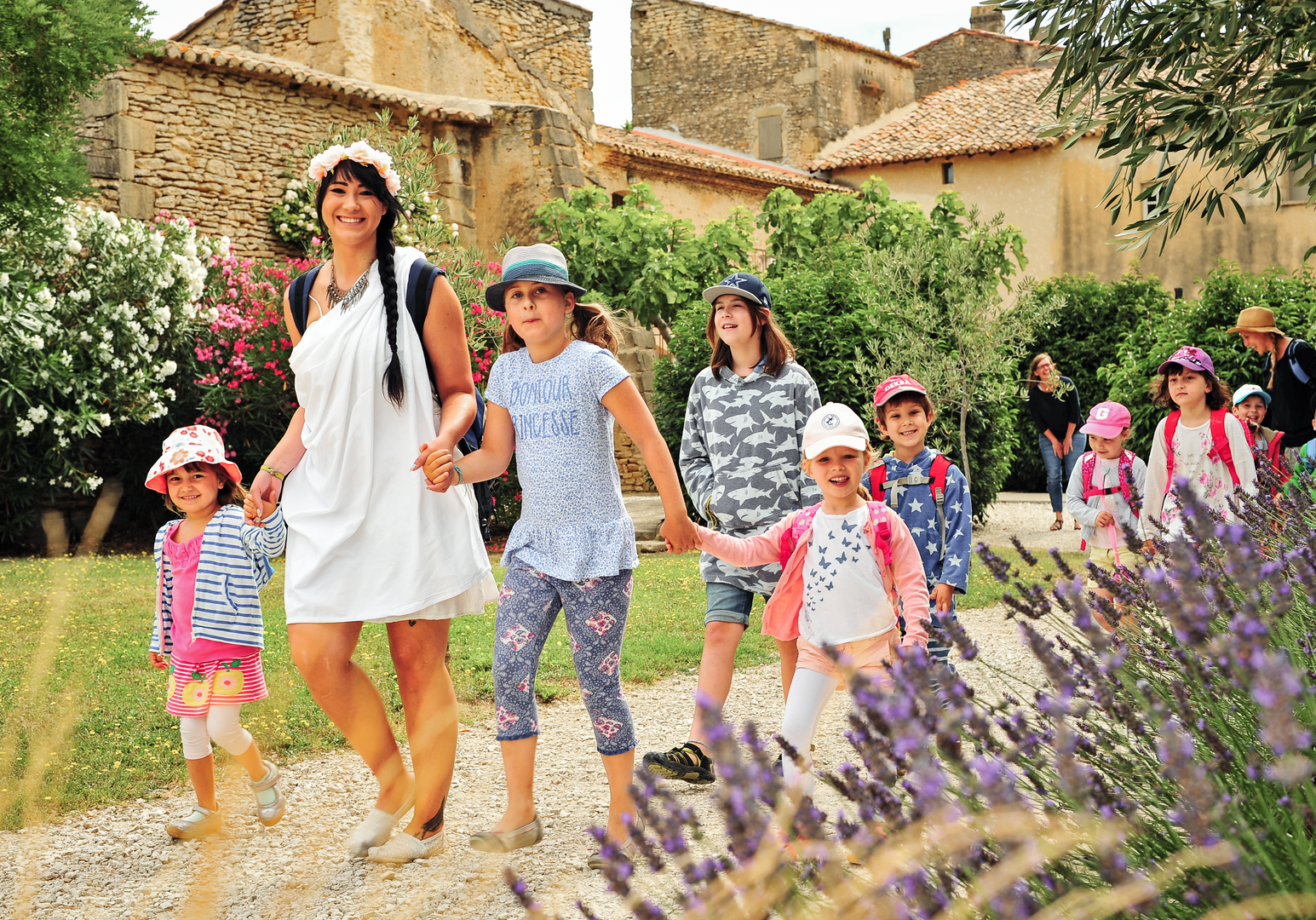 Kinder laufen fröhlich in einer Gruppe durch einen Garten mit Blumen