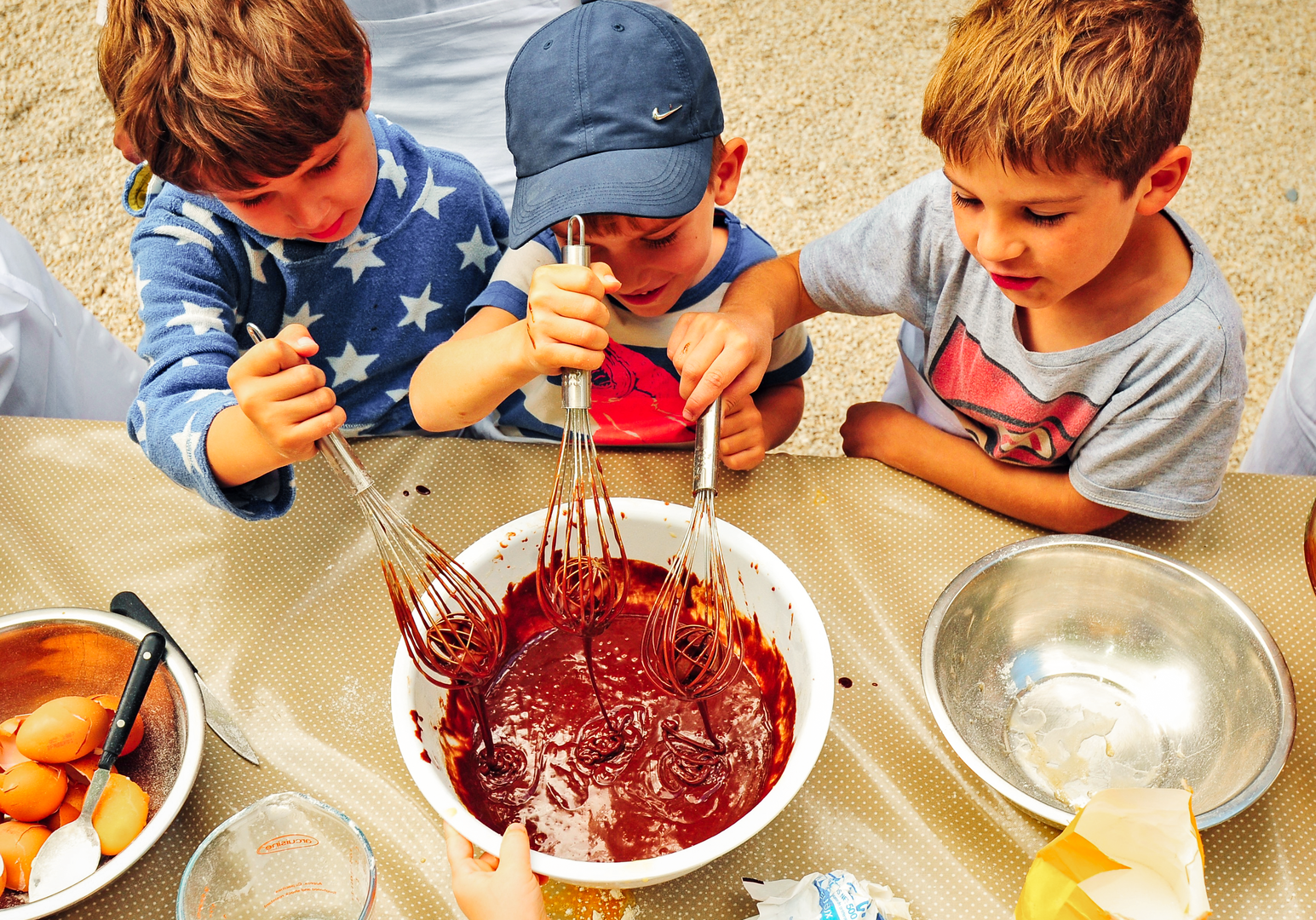 Kinder bereiten gemeinsam Teig oder Marmelade in einer Küche zu