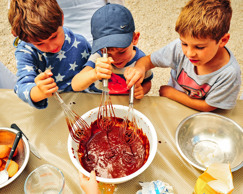 Kinder bereiten gemeinsam Teig oder Marmelade in einer Küche zu