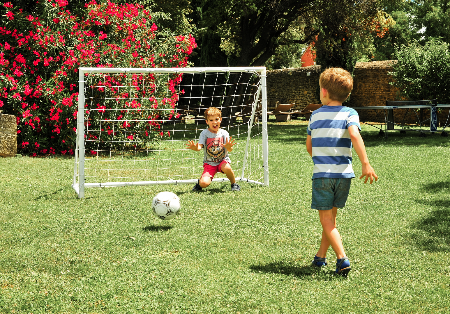 Kinder spielen Fußball auf einer Wiese mit kleinem Tor