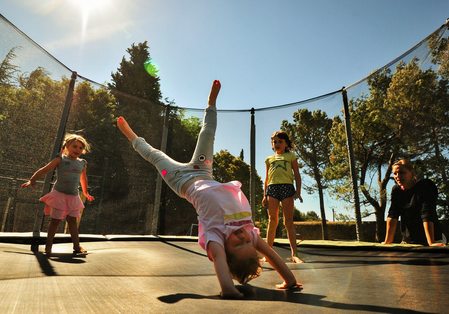 Kinder springen und machen Tricks auf einem Trampolin im Freien