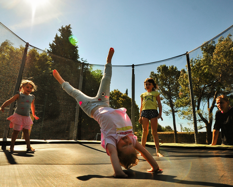 Kinder springen und machen Tricks auf einem Trampolin im Freien