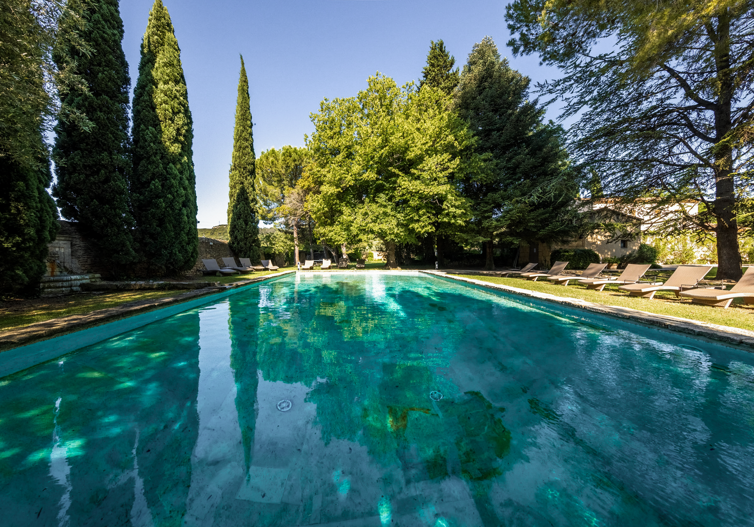 Pool in einem Garten, umgeben von Bäumen und Liegestühlen
