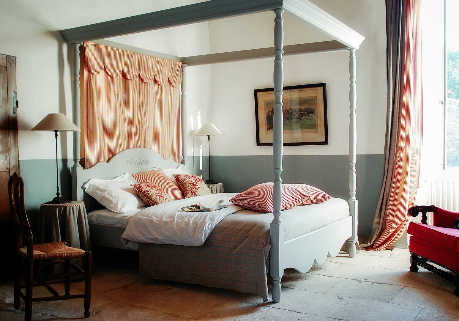 Himmelbett mit rosa Vorhängen und rotem Sessel