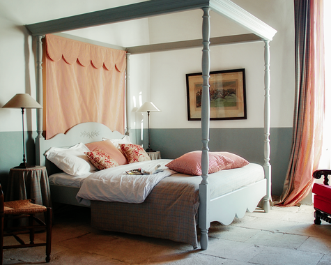 Himmelbett mit rosa Vorhängen und rotem Sessel