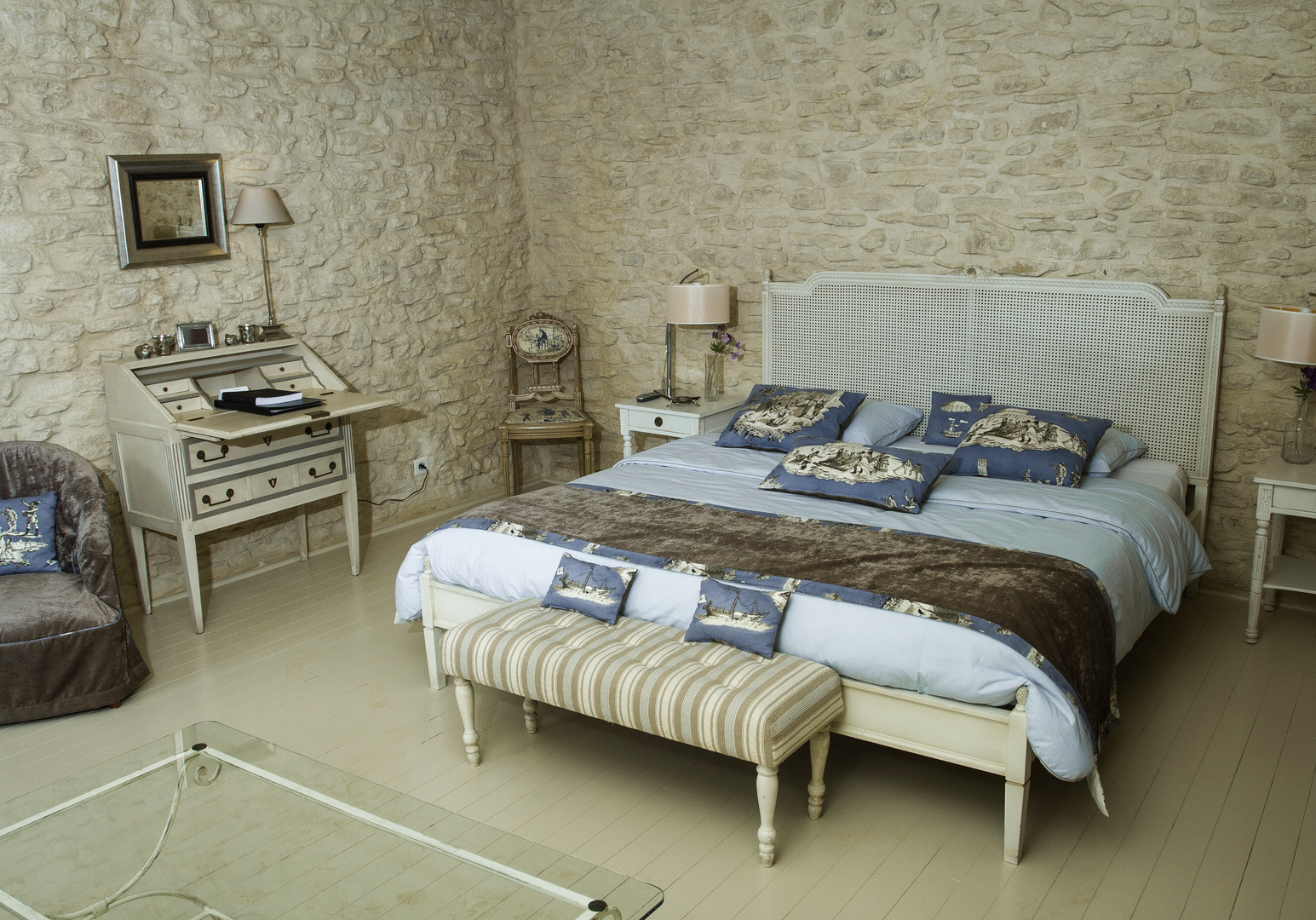 Doppelbett mit gemusterter Tapete, Hocker und Schreibtisch