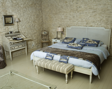 Doppelbett mit gemusterter Tapete, Hocker und Schreibtisch