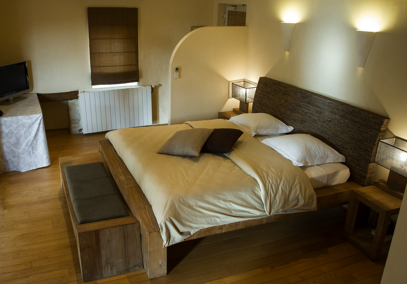 Zimmer mit Doppelbett, Wandleuchte und warmem Licht