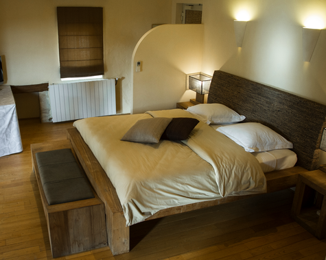 Zimmer mit Doppelbett, Wandleuchte und warmem Licht