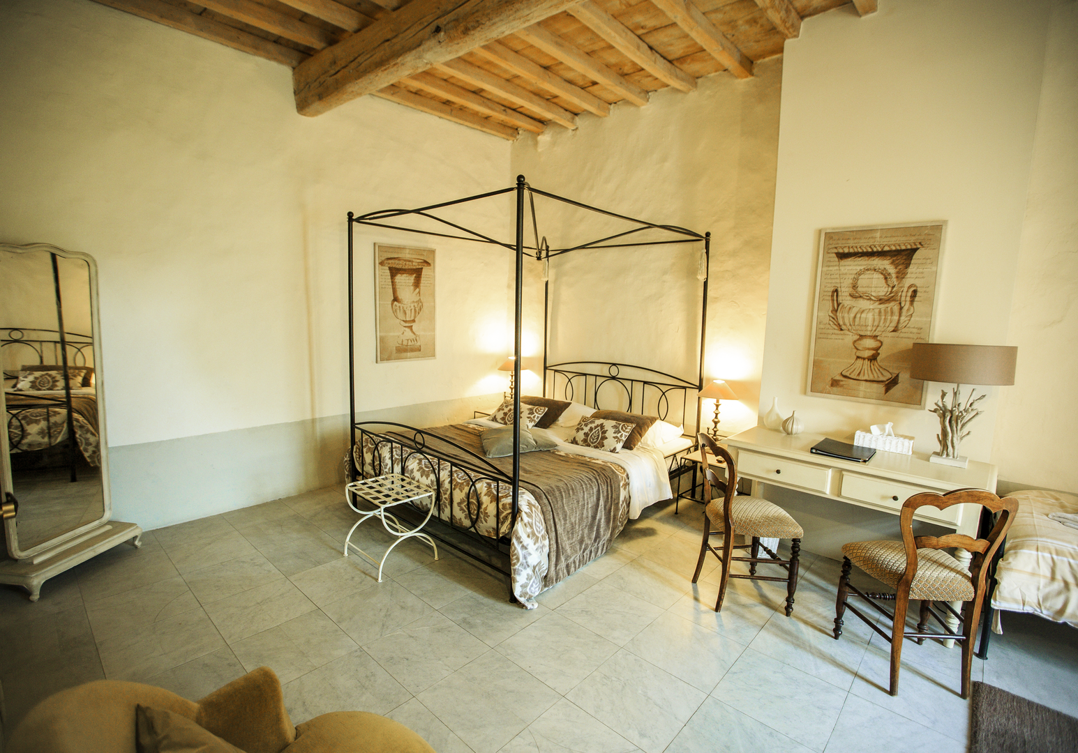 Schlafzimmer mit Metallbett, Spiegel, Schreibtisch und Holzbalken