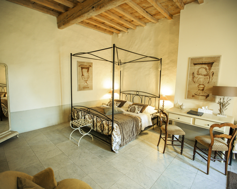 Schlafzimmer mit Metallbett, Spiegel, Schreibtisch und Holzbalken