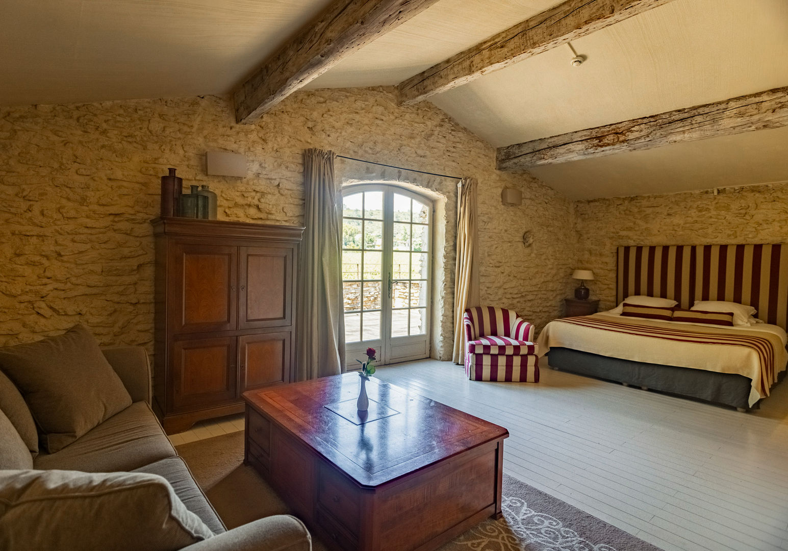 Helles Zimmer mit Doppelbett, Holztruhe und Steinwand