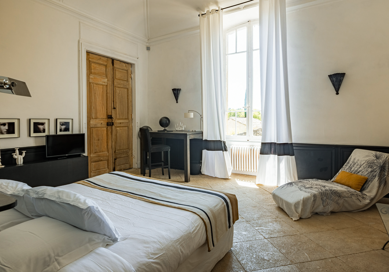 Schlafzimmer mit Doppelbett, Holztür und langen Vorhängen