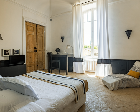Schlafzimmer mit Doppelbett, Holztür und langen Vorhängen