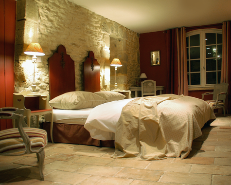 Schlafzimmer mit zwei Einzelbetten, Steinwand und antiken Möbeln