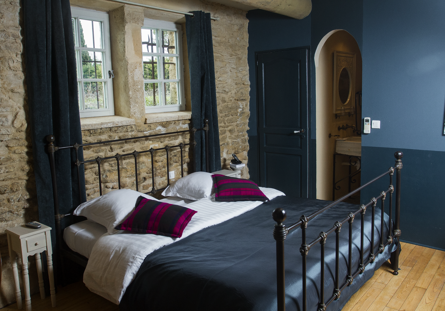 Schwarzes Metallbett mit lila Kissen und blauer Wand