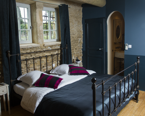 Schwarzes Metallbett mit lila Kissen und blauer Wand