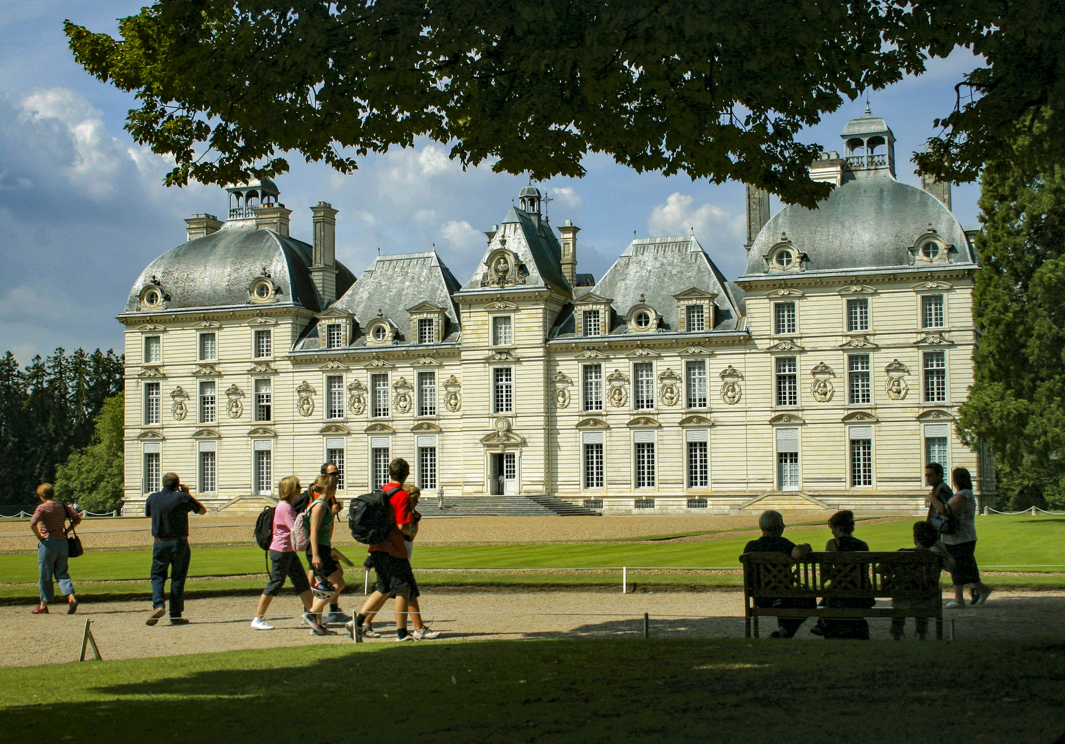 Prächtiges Schloss mit Garten, Menschen spazieren auf der Wiese davor