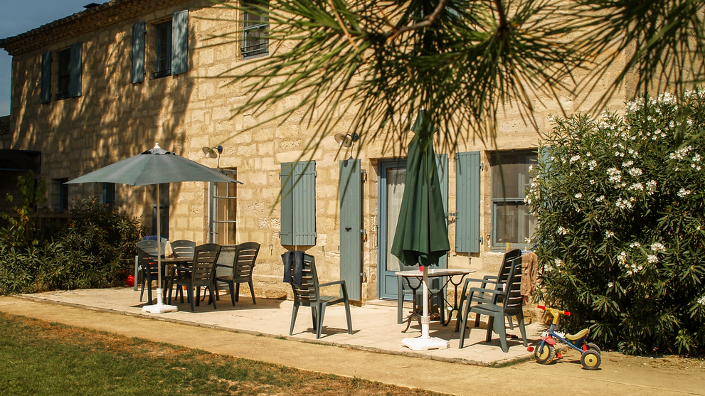 Landhaus mit Terrasse und Sitzplätzen im Freien, umgeben von Pflanzen und Bäumen