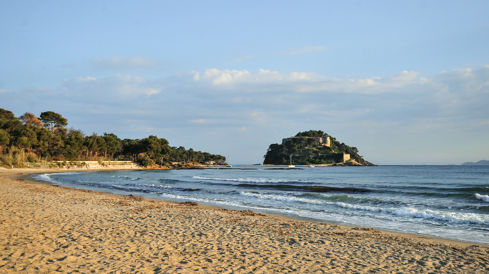 Ruhiger Sandstrand mit Blick auf kleine Insel im Meer