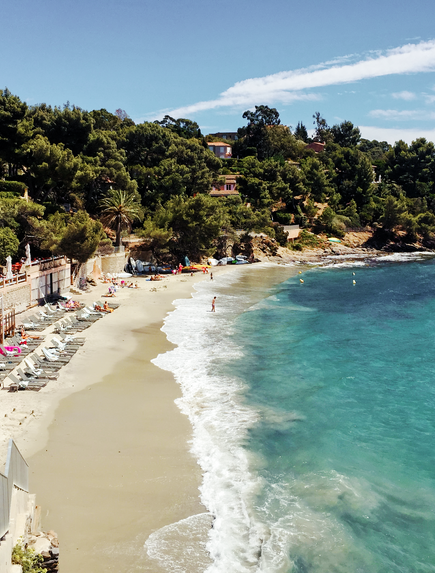 Küstenstrand mit türkisfarbenem Wasser und bewaldeter Bucht