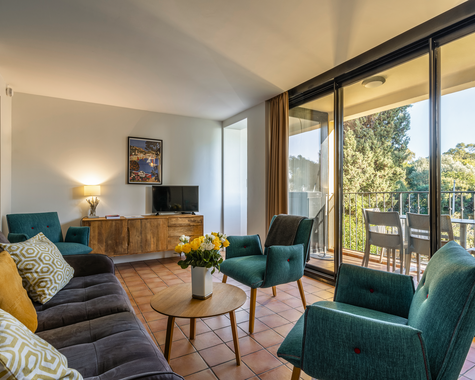 Heller Wohnbereich mit türkisen Sesseln und großer Glasfront zum Garten