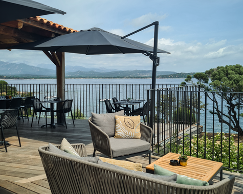 Lounge-Bereich auf Holzterrasse mit Blick auf das Meer