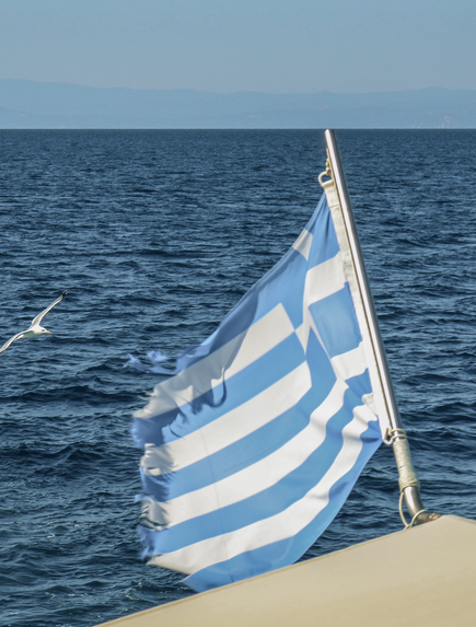Griechische Flagge weht auf einem Boot vor dem offenen Meer