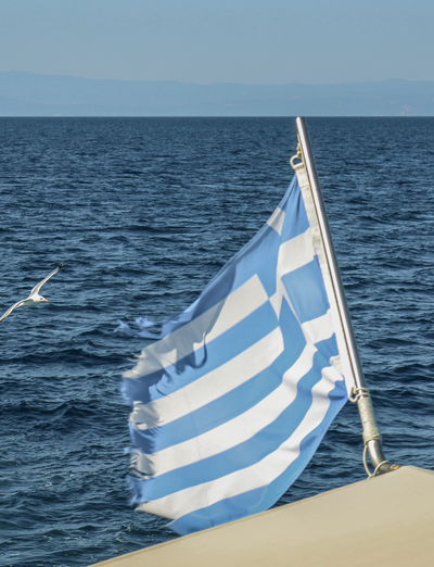 Griechische Flagge weht auf einem Boot vor dem offenen Meer