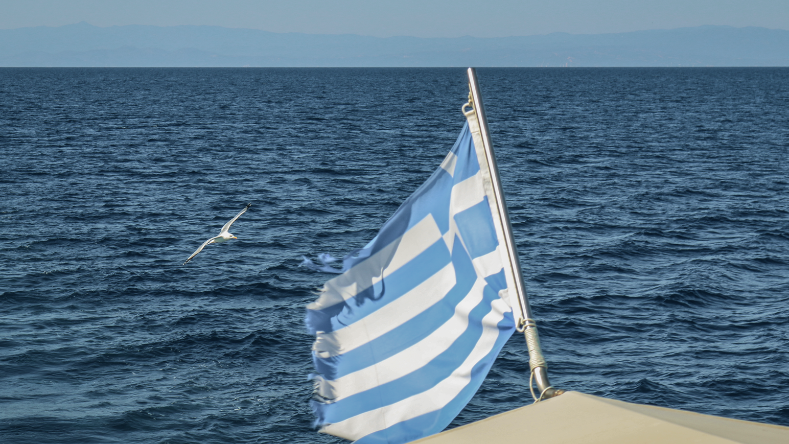 Griechische Flagge weht auf einem Boot vor dem offenen Meer