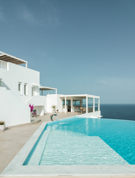 Moderner Infinity-Pool vor weißer Architektur und blauem Meer