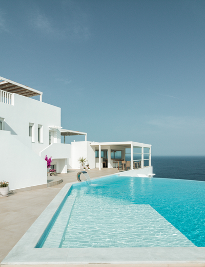 Moderner Infinity-Pool vor weißer Architektur und blauem Meer