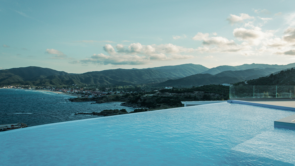 Infinity-Pool mit weitem Blick auf Küstenlandschaft und Berge