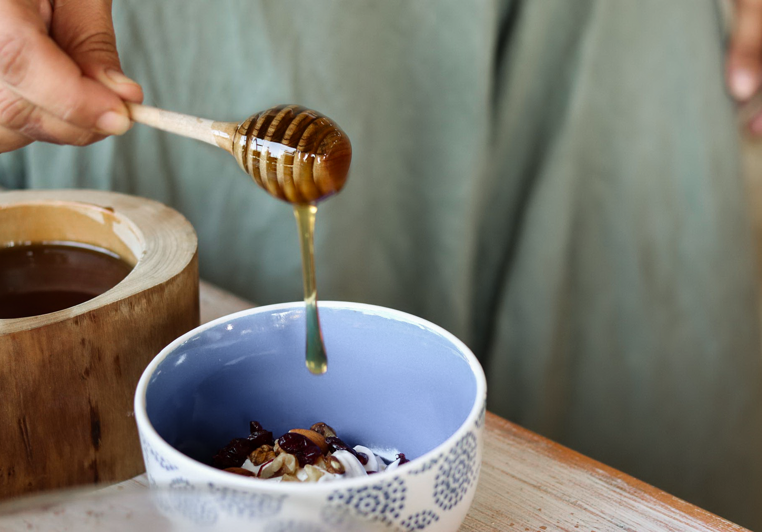 Honig wird in eine Schale mit Joghurt und Früchten gegossen