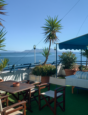 Terrasse mit Sitzplatz und Blick auf das Meer bei blauem Himmel 