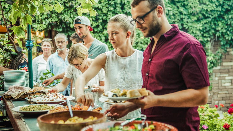 Personen füllen sich Essen auf Teller