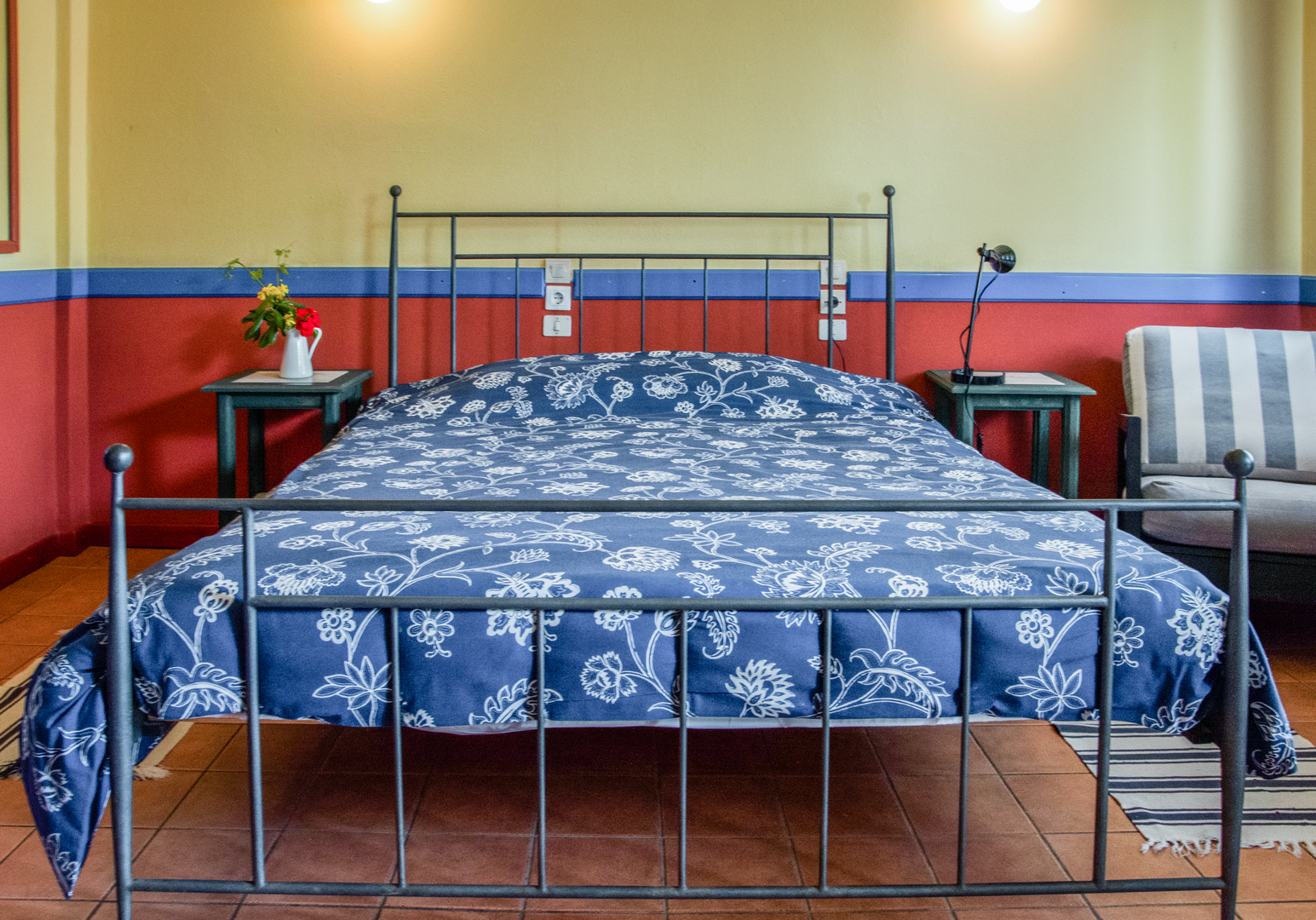 Doppelbett mit blauer Decke und orangefarbener Wand